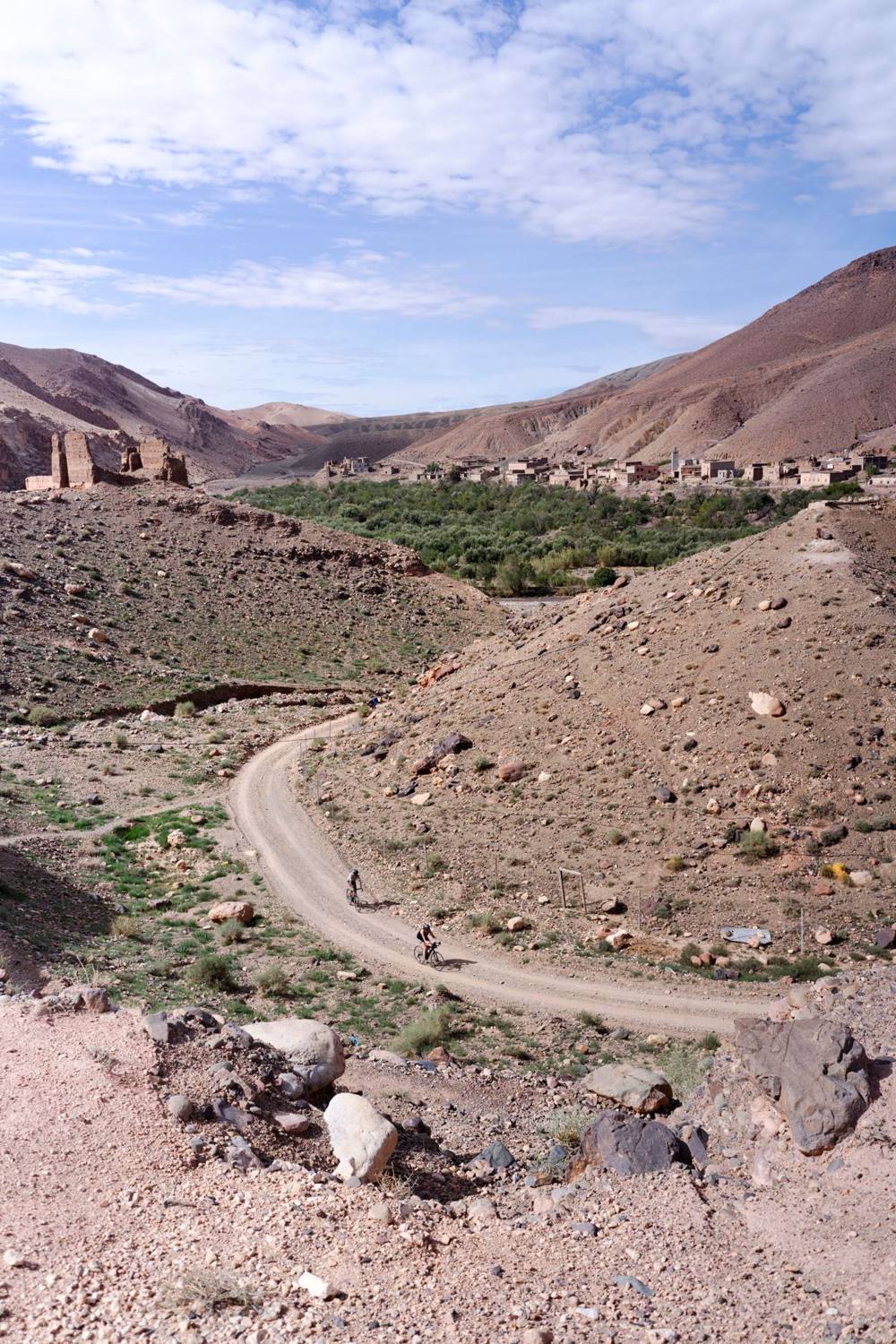 Two riders on a gravel road through the mountains